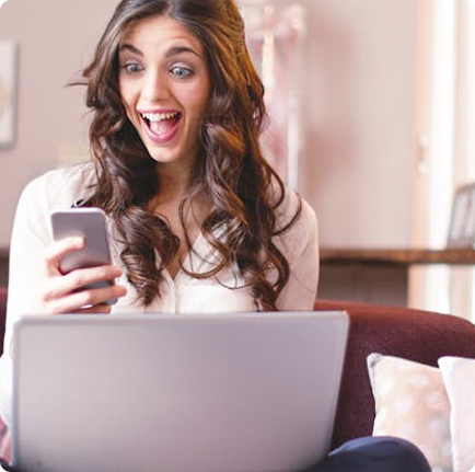 Woman excited looking at laptop and phone
